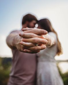 a man and woman holding each other's hands in front of the camera with their arms wrapped around them