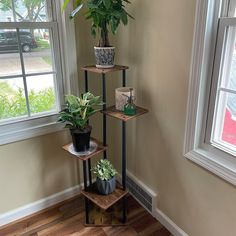 three tiered plant stand next to a window with potted plants on it in the corner