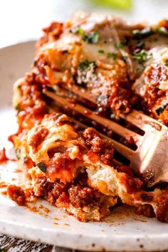 a close up of a plate of lasagna with a fork stuck in it