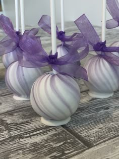 four white and purple striped candy lollipops on a wooden table with ribbons