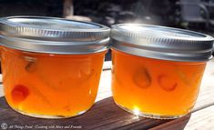 two jars filled with liquid sitting on top of a wooden table