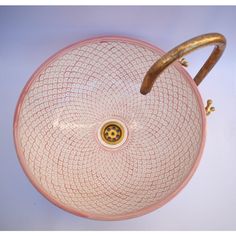 a pink and white sink with a wooden handle on it's side, against a blue background