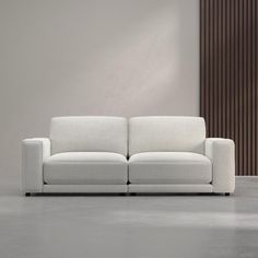 a white couch sitting on top of a cement floor next to a wooden paneled wall