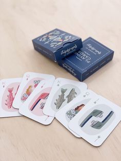 four playing cards sitting on top of a wooden table next to a blue card box