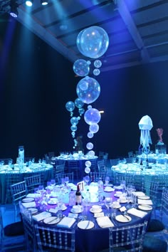 To access the dining area guests made their way through an opulent deep wall of fabric columns, emulating waves and shafts of light in the sea. Dining tables were dressed in four different shades of blue cloths, surrounded with clear perspex chairs. Bubble, coral and internally illuminated jelly fish table centres combined with creative under the sea lighting brought the space to life and left guests utterly in awe as 3mtr jellyfish acrobats danced the night away over the top of the tables. Water Themed Decorations, Under The Sea Luxury Party, Under The Sea Gala Dress, Dinner And Dance Theme Ideas, Under The Sea Debut Theme, Under The Sea Party Theme Decoration, Jellyfish Quince Theme, Prom 2023 Theme, Jellyfish Quince