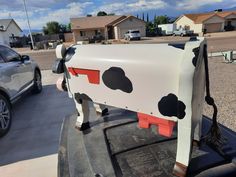 a cow statue is on the back of a truck in a parking lot next to houses