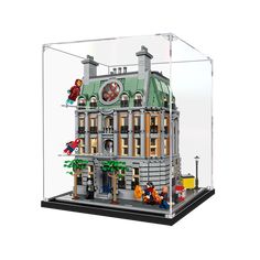 a lego model of a building in a glass case on a white background, with people standing outside