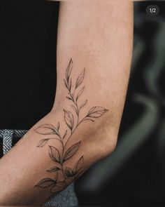 a woman's arm with a tattoo on it that has leaves growing out of it