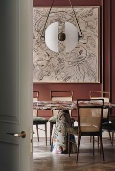 a dining room with chairs and a painting hanging on the wall above it's doorway