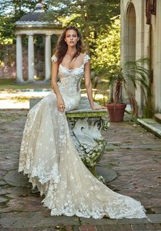 a woman in a wedding dress sitting on a stone bench with her hand on her hip