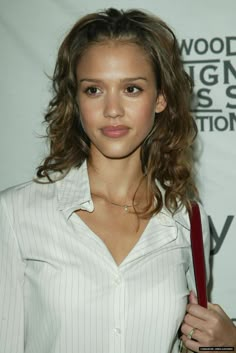 a beautiful young woman holding a red purse