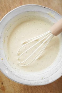 a whisk in a white bowl on a wooden table