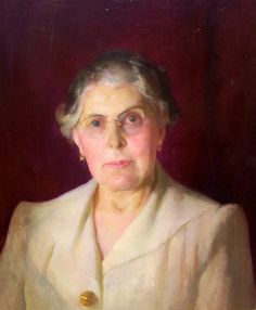 an old woman in a white coat and gold brooch is looking at the camera