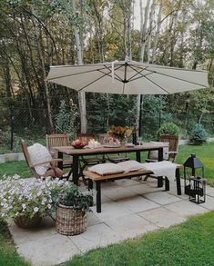 an outdoor dining area with table, chairs and umbrella in the middle of the yard