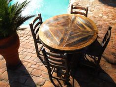 an outdoor table and chairs next to a pool with a potted plant on it