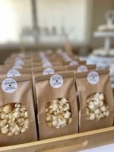 four bags filled with popcorn sitting on top of a wooden tray next to each other