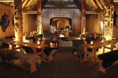 a room filled with wooden tables and benches covered in fur on top of hard wood flooring