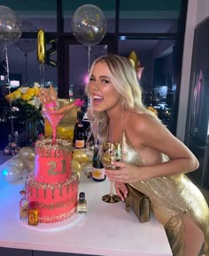 a woman sitting at a table in front of a pink birthday cake with gold decorations