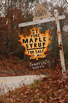 a sign that is sitting on the side of a road in front of some trees