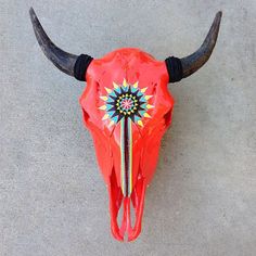 a red bull's skull with long horns on the cement floor, viewed from above