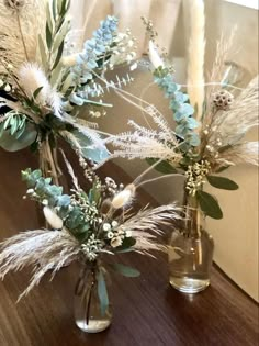 two vases filled with flowers and plants on a table