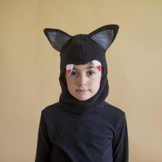 a young boy wearing a black cat costume with red and white ears on his head