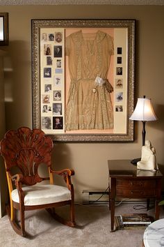 an old fashioned rocking chair in front of a framed dress