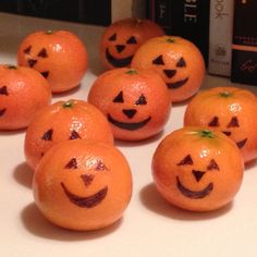 several oranges with faces drawn on them sitting next to a bookcase and some books