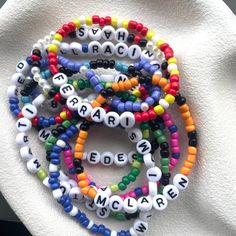 several bracelets with letters on them sitting on top of a white cloth covered napkin