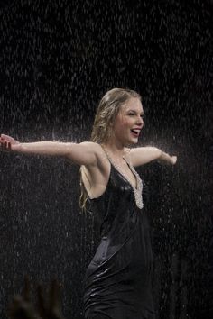 a woman standing in the rain with her arms outstretched