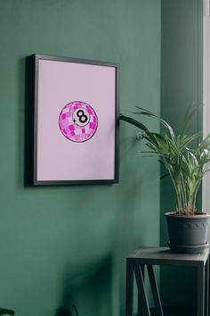 a green wall with a potted plant and a pink poster hanging on the wall