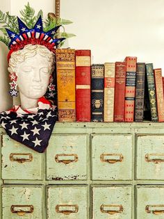 an old dresser with books and a statue of liberty on top