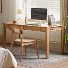 a wooden desk with a computer on top of it next to a chair and window