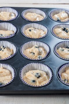 a muffin tin filled with cupcake batter and blueberries in the bottom half