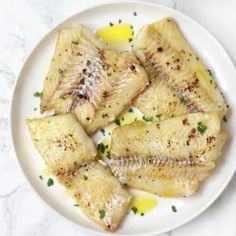 fish fillets on a white plate topped with parsley