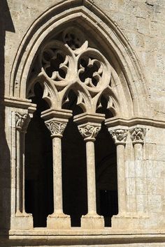 an old stone building with columns and arches on the outside, in front of a window