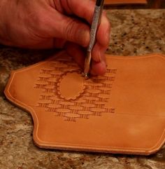 a person using a carving tool on a piece of leather