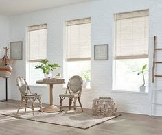 a living room filled with furniture and windows covered in shades of white brick wallpaper