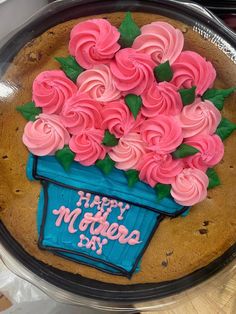 a cake with pink frosting and flowers in a blue flower pot on top of it