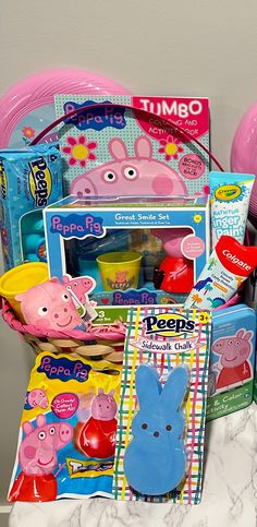 a basket filled with peppa pig toys on top of a marble counter next to balloons