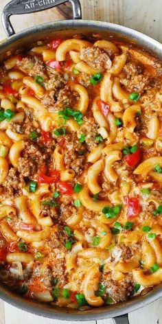 a pot filled with pasta and meat on top of a wooden table