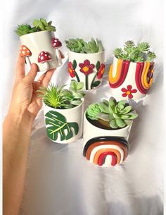 a person is holding some plants in their hand and they are painted with different colors