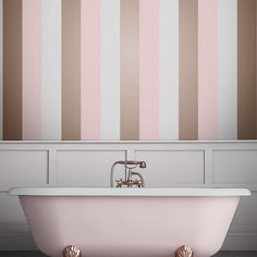 an old fashioned bathtub in front of a striped wall with pink and white stripes