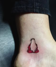 a small tattoo on the ankle of a woman's foot with a red bow