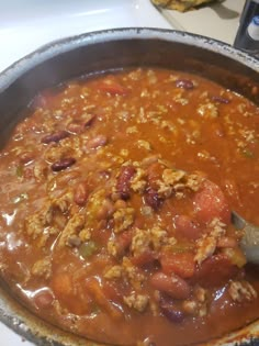 a pot filled with chili and meat on top of a stove