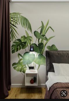 a bed room with a neatly made bed and a plant wall mural on the wall