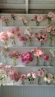 pink and white flowers are arranged on shelves