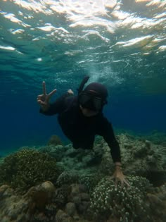 a person wearing a scuba suit and diving in the water with their hand up to the camera