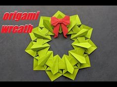 an origami wreath made out of green paper with a red bow on top