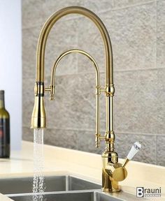 a kitchen faucet with water running from it's spout, next to a bottle of wine